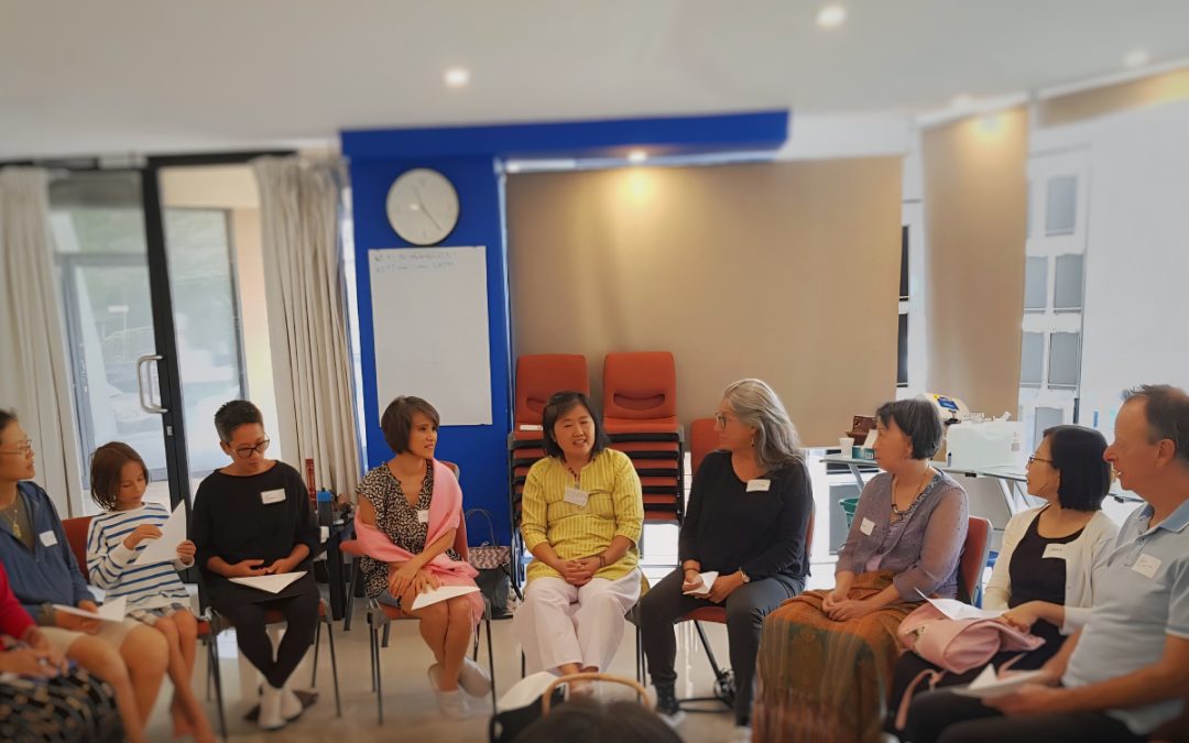People sitting on chairs arranged in a semi circle discussing teacher training