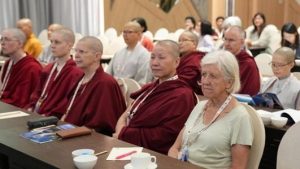 A room of Buddhist women sitting at desks at a conference.