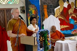 Buddhist monk speaking at a lectern.